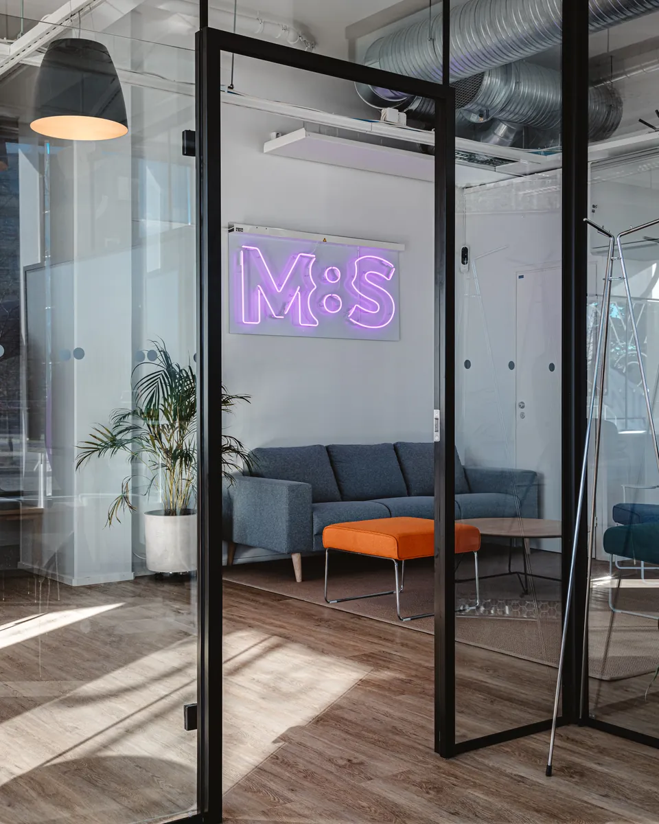 Glass-walled meeting room and the M8S neon sign